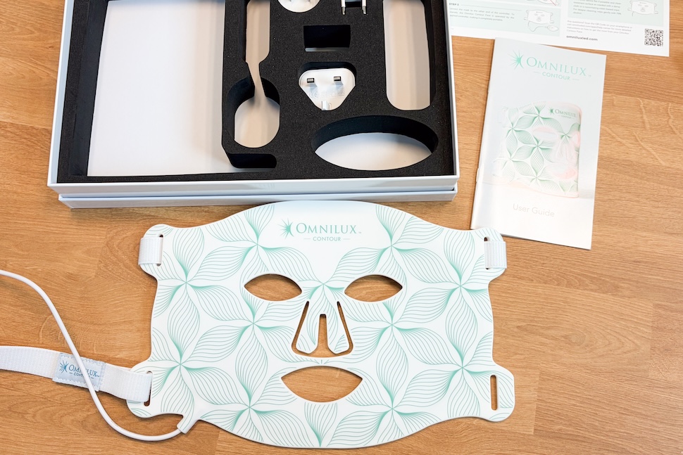 An open box containing the Omnilux Contour Face mask and its accessories.