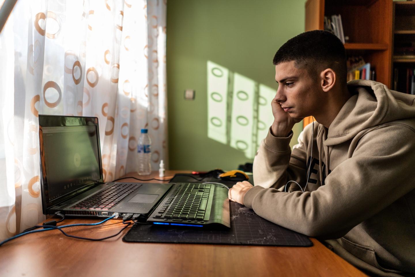 Young man looks sadly at computer at home