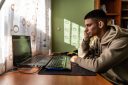 Young man looks sadly at computer at home