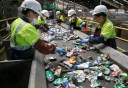 A team of workers sort aluminum cans near large bales of plastics