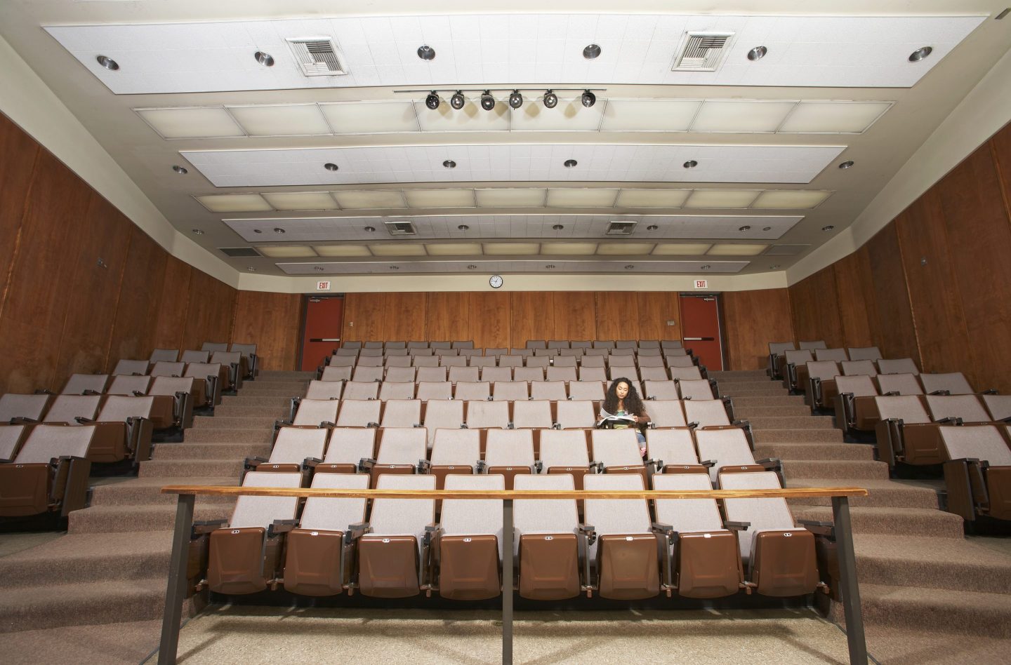 Female student reading in empty classroom auditorium, low angle view