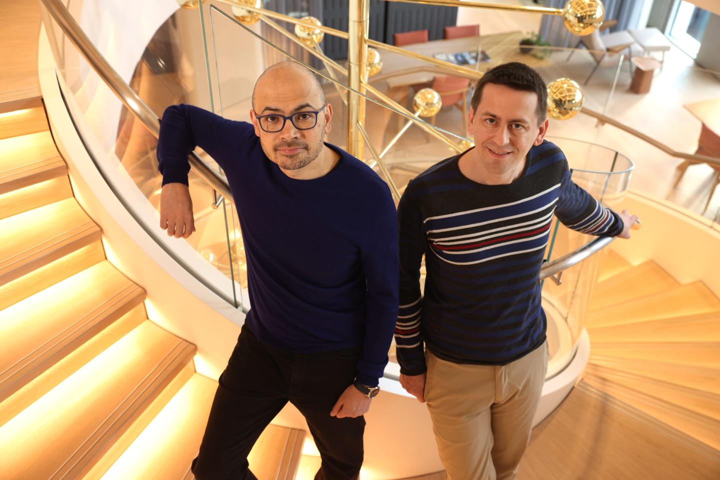 Google DeepMind CEO Demis Hassabis (left) stands on a spiral staircase next to Google DeepMind researcher John Jumper.