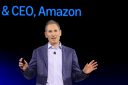 Andy Jassy speaks in front of a black and blue background.
