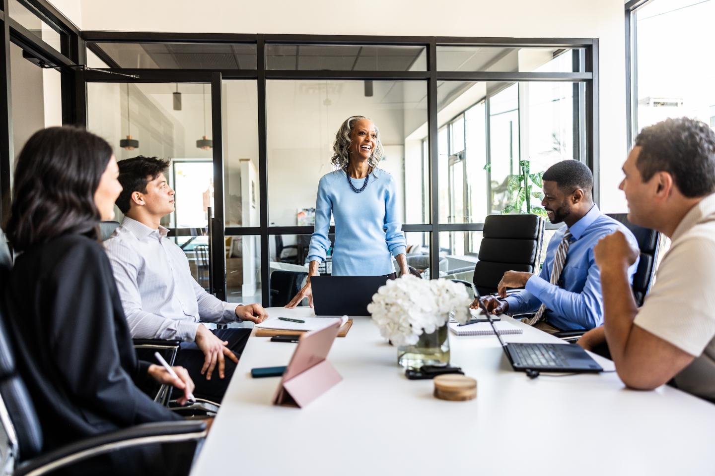 Senior businesswoman speaking to colleagues in modern conference room