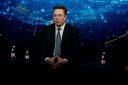 elon musk poses while wearing a suit
