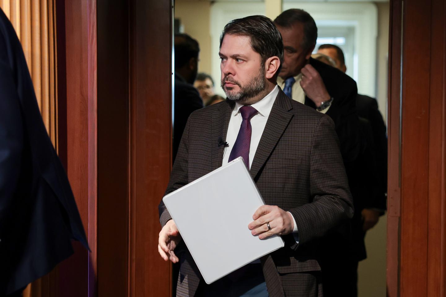 Senator Ruben Gallego arriving with a binder in hand at a news conference on Capitol Hill.