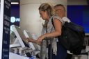 A woman types into a kiosk at an airport.