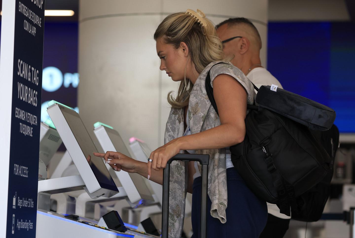A woman types into a kiosk at an airport.