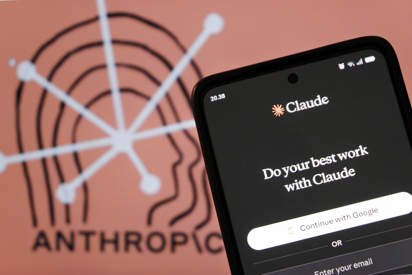 Anthropic logo behind phone with Claude logo.