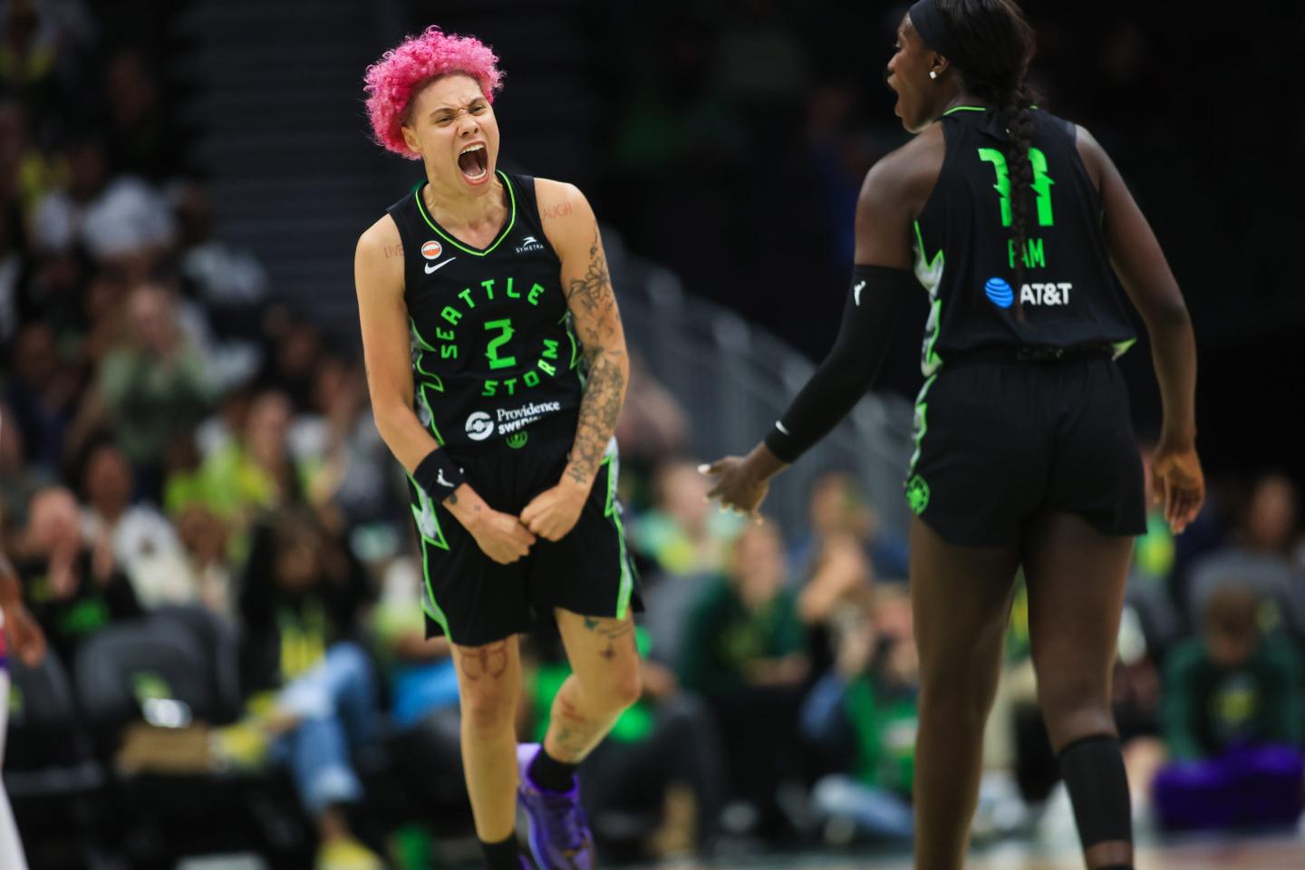 Natisha Hiedeman, wearing a black and green jersey, celebrates on court.