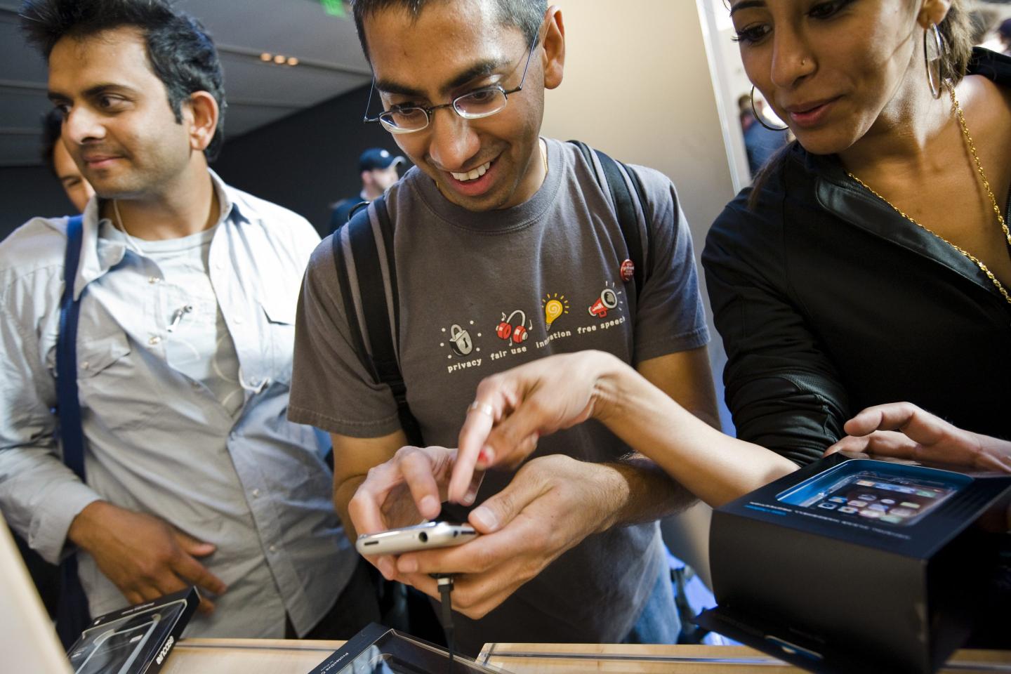 A person holds an iPhone as someone next to them points at the screen.