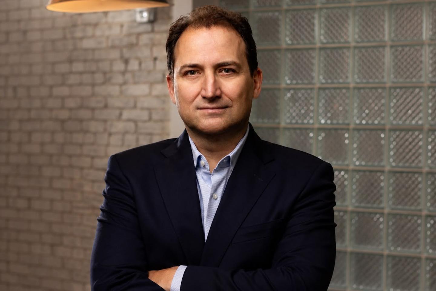 Itai Ben-Zaken poses with his arms crossed while wearing a suit.