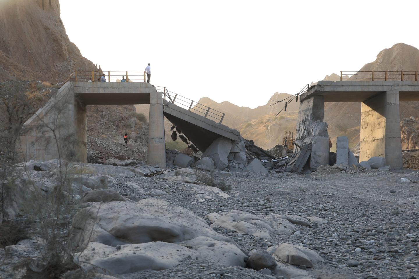People stand on a bridge destroyed after a strike in Hormozgan province, southern Iran, Saturday, July 18, 2026. 