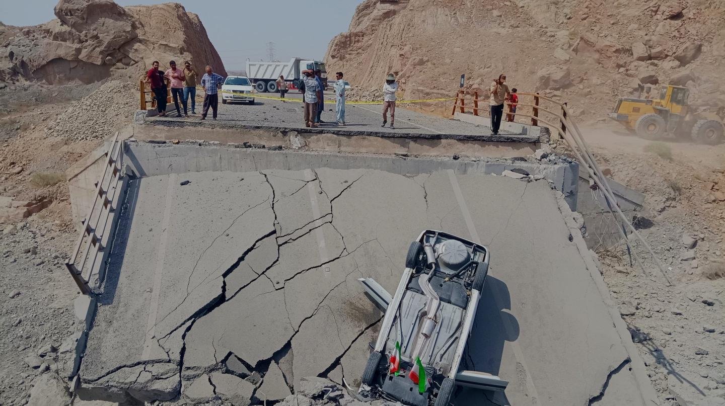 An overturned car sits on a section of a destroyed bridge after a strike in Hormozgan province, southern Iran, Saturday, July 18, 2026.