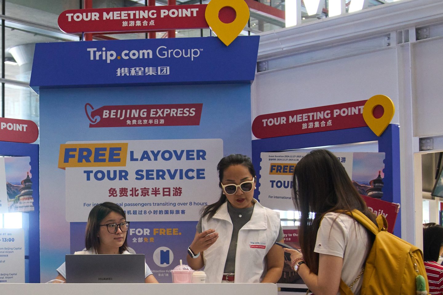 Workers help a traveler at a Trip.com tabling session booth.