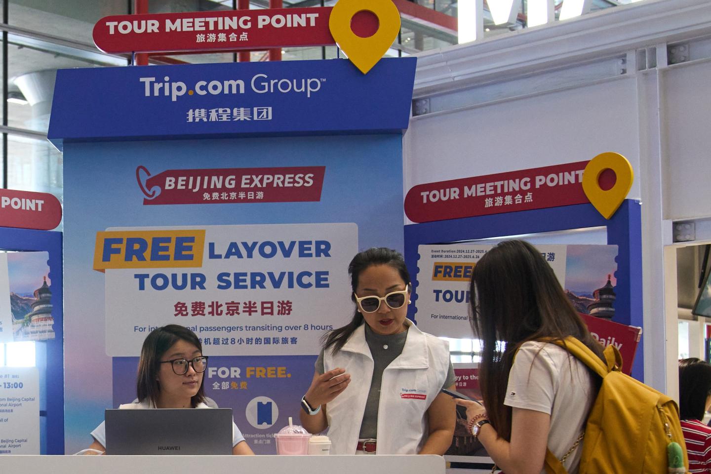 Workers help a traveler at a Trip.com tabling session booth.