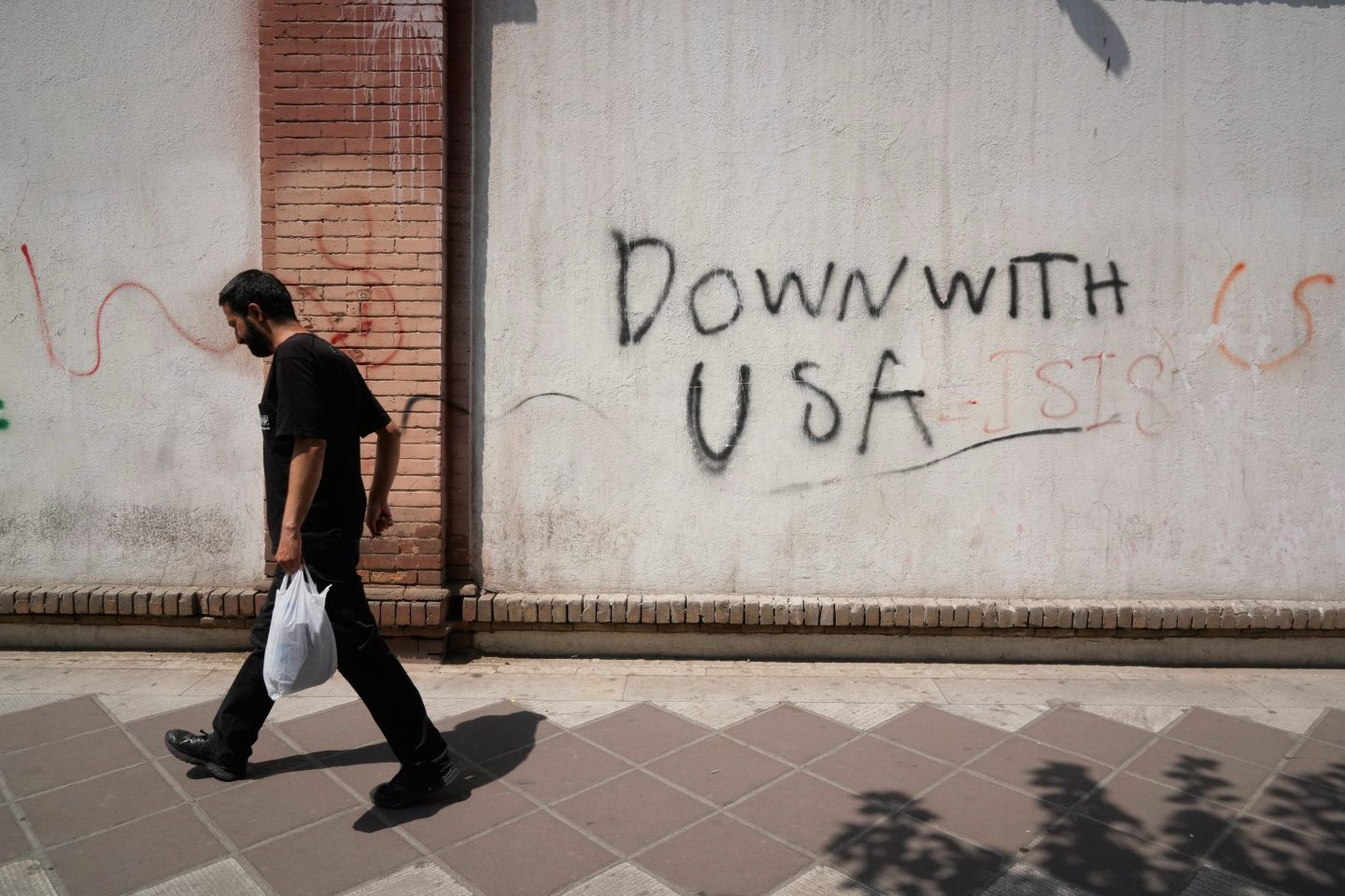 Photo of man walking past anti-U.S. graffit "Down with USA" in Tehran