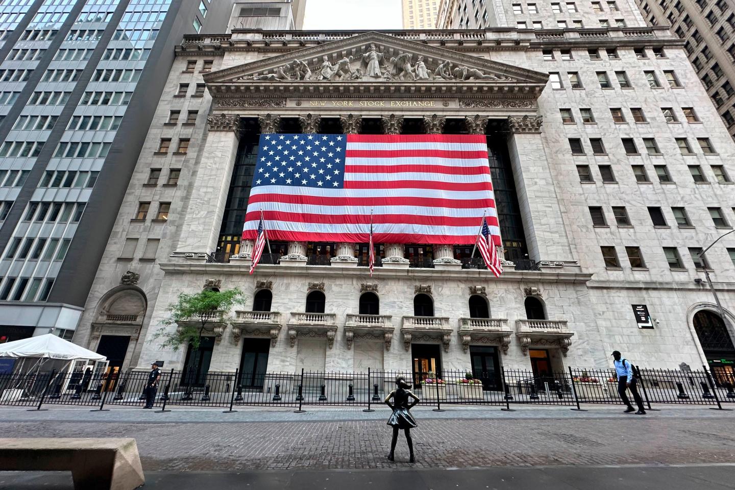 People pass the New York Stock Exchange on the street.