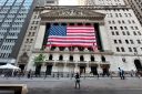 People pass the New York Stock Exchange on the street.