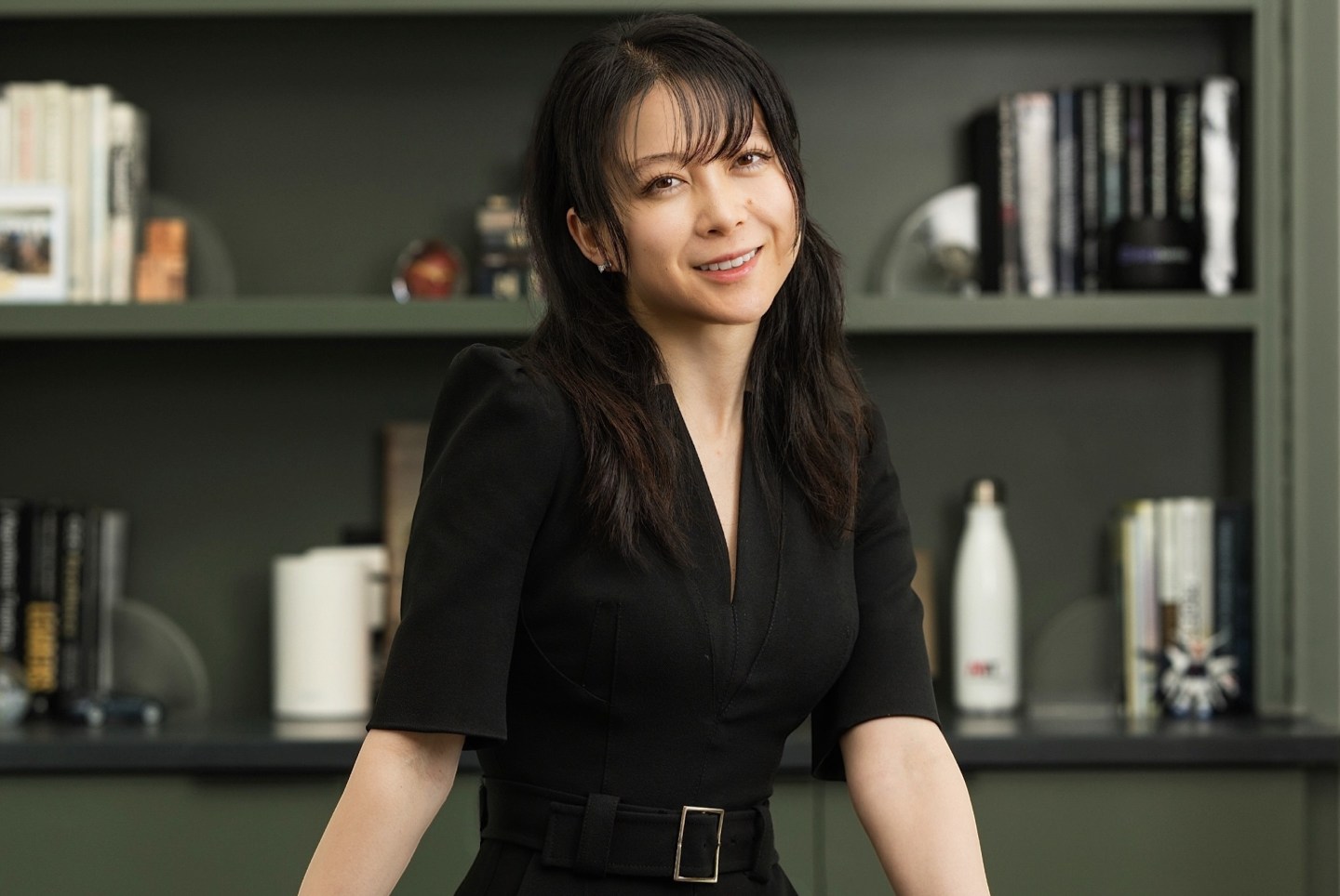 Christina Qi smiles in front of a bookshelf