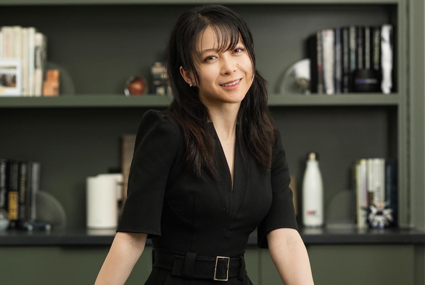Christina Qi smiles in front of a bookshelf