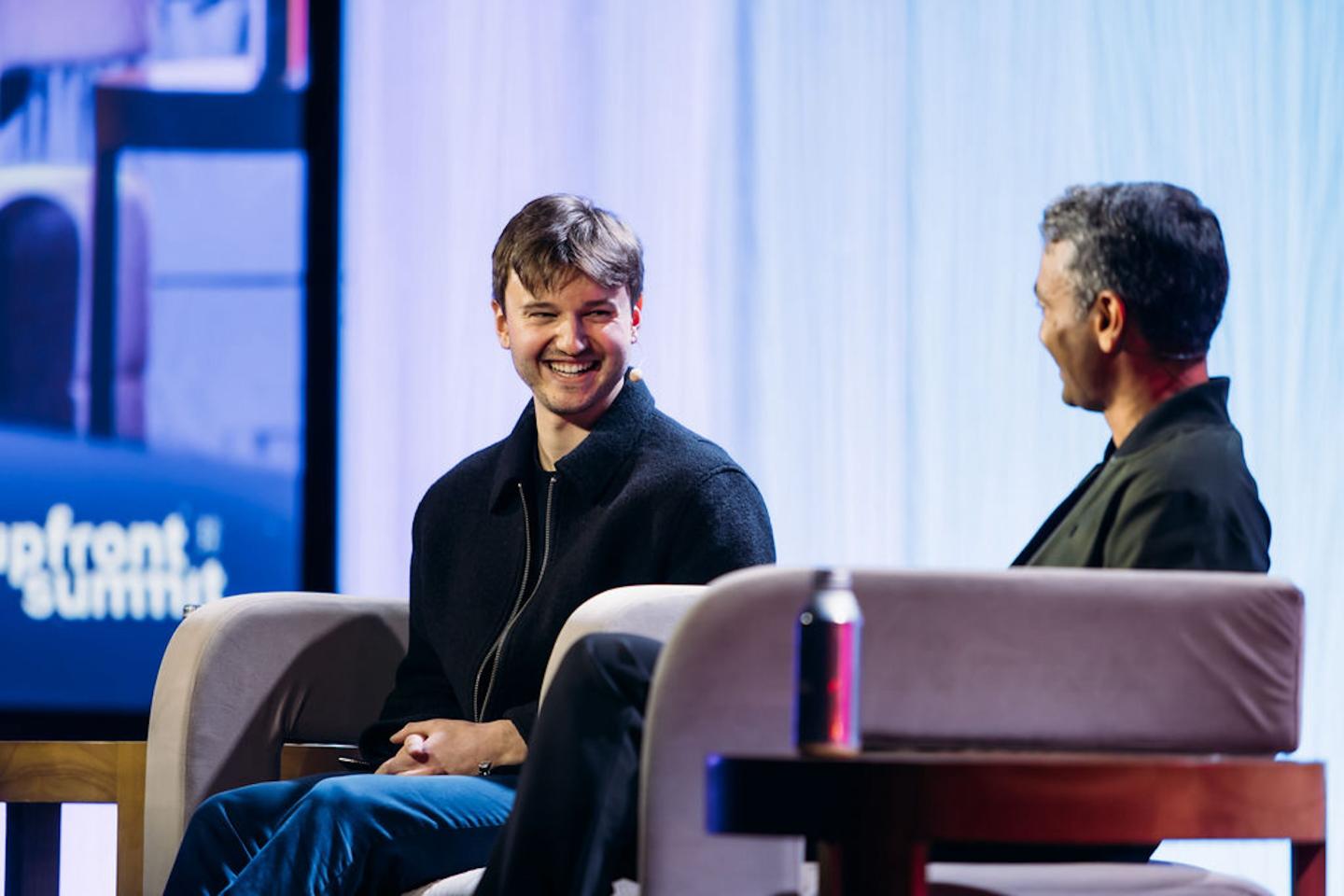 Brendan Foody smiles on stage sitting in a chair.