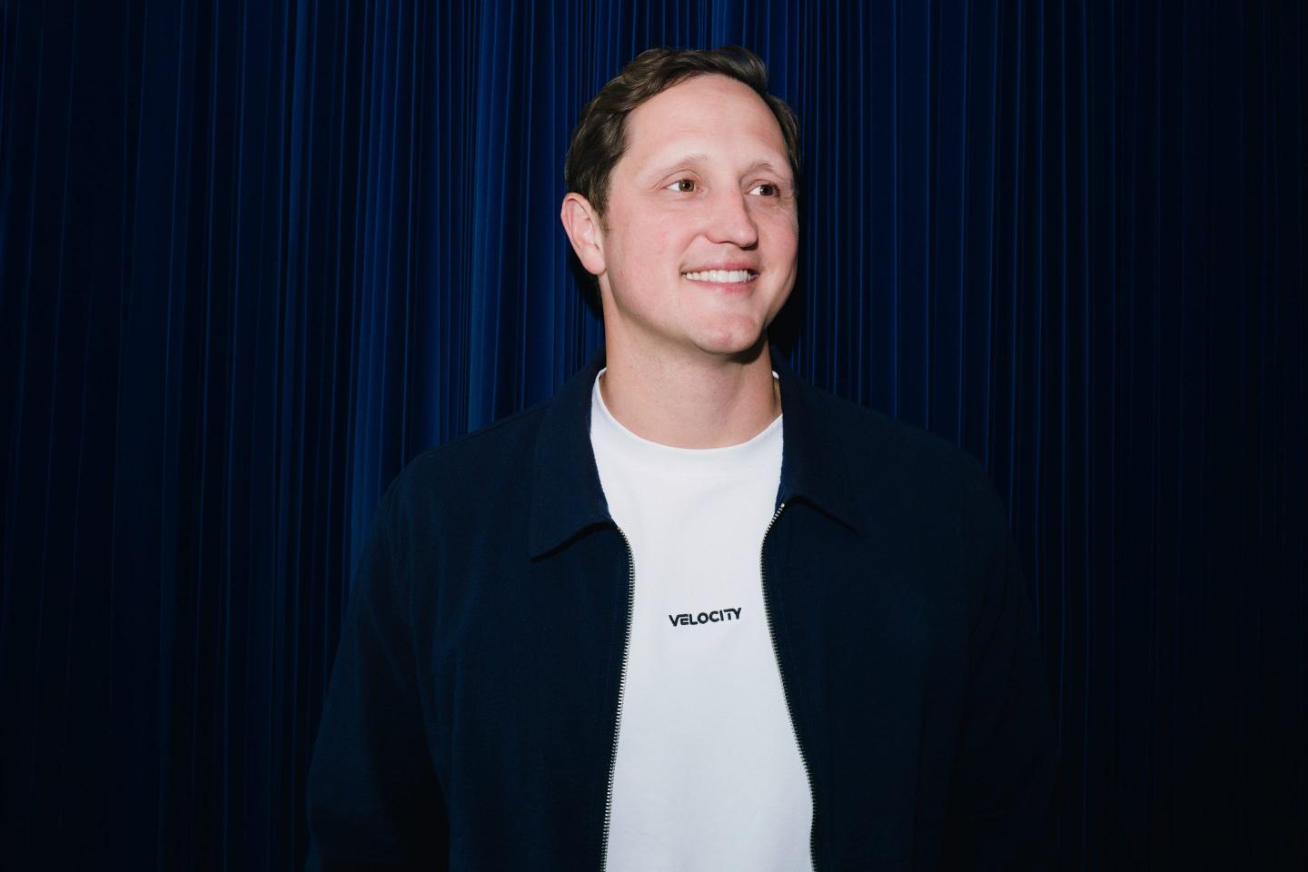 Velocity CEO Eric Queathem smiles as he looks to the far left.