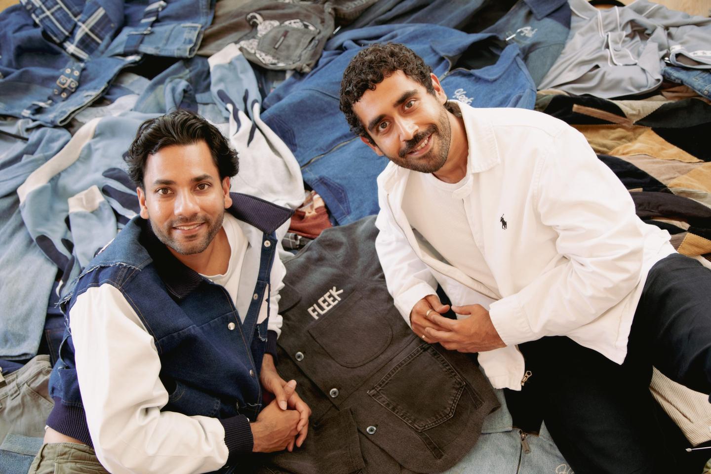 Fleek cofounders Sanket Agarwal and Abhi Arora pictured reclining on a pile of vintage clothing.