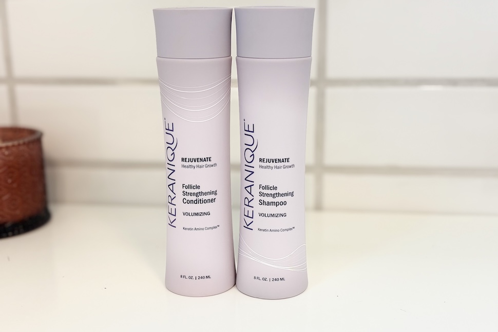 A bottle of Keranique Rejuvenate Follicle Strengthening Conditioner and Follicle Strengthening Shampoo sitting next to each other on a white countertop.