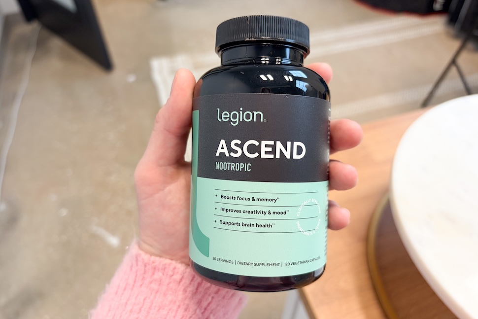 Closeup of a hand holding a bottle of Legion Ascend Nootropic supplements