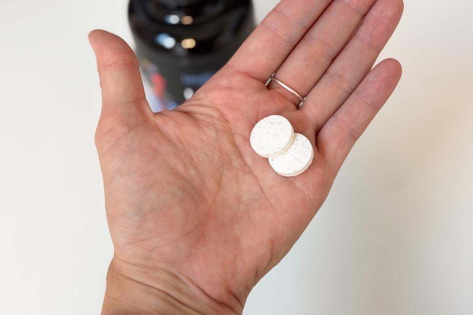An open palm holding two Legion Lunar Sleep Aid tablets