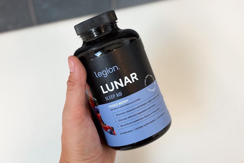 A hand holding a bottle of Legion Lunar Sleep Aid