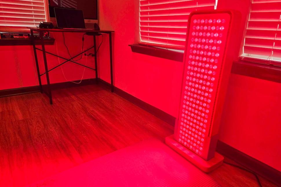 The Sunlighten Red Light Therapy Panel sitting in a home office, fully lit up
