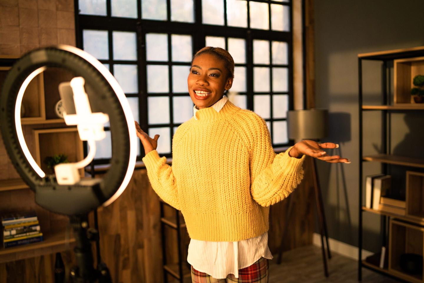 woman yellow shirt standing in front of ring light