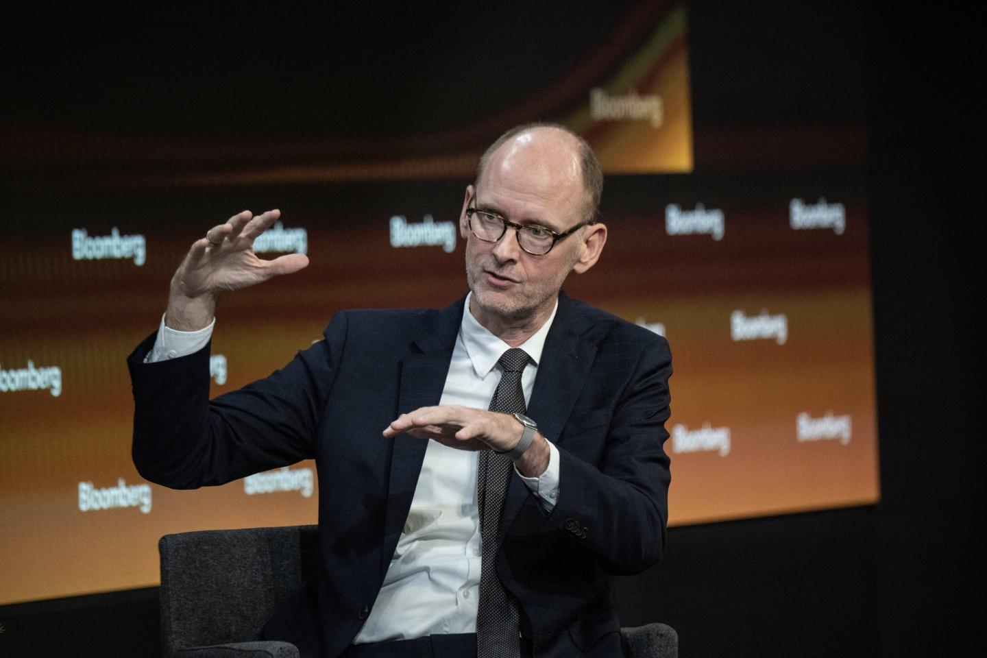 Torsten Slok holds his hands apart as he speaks on stage.