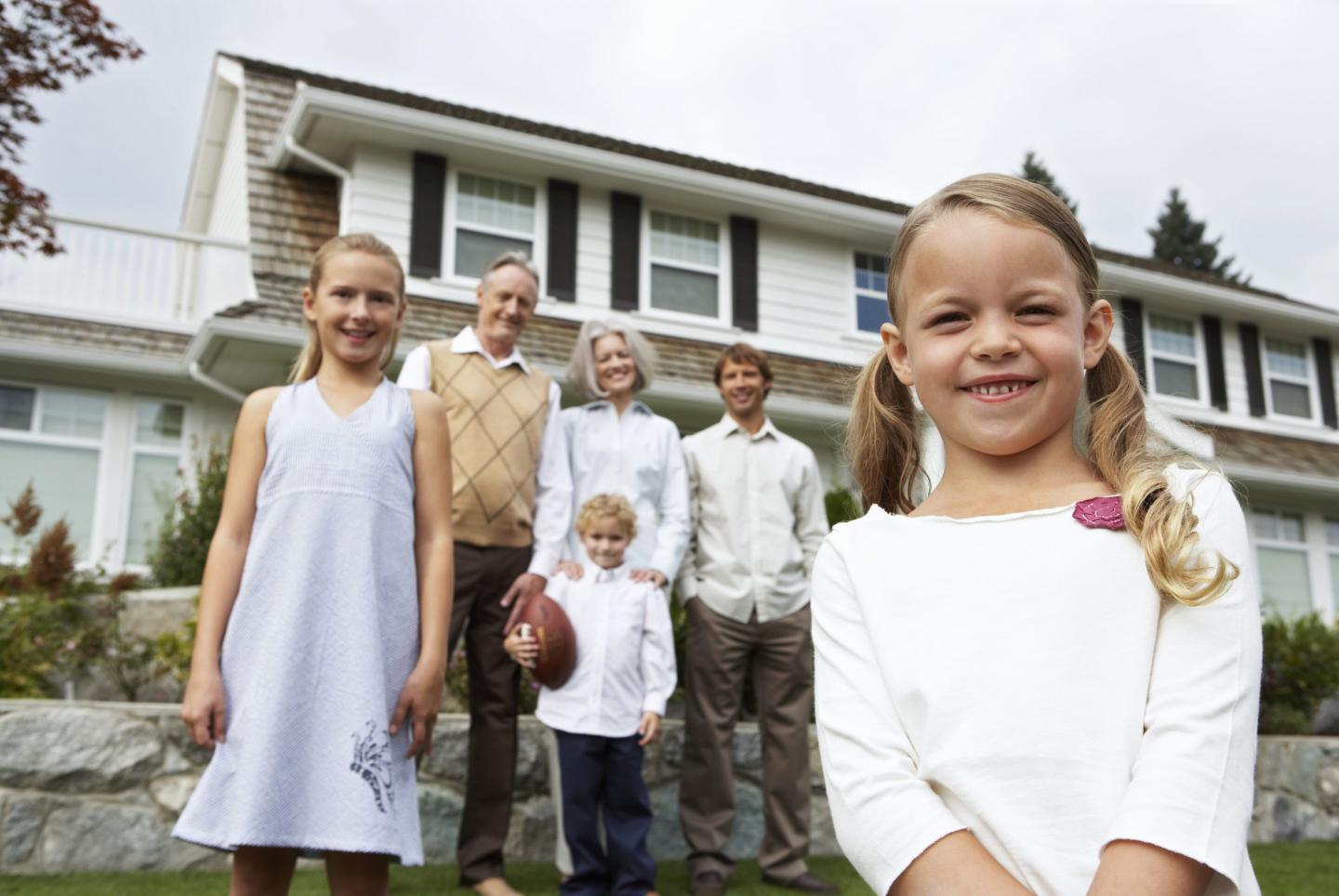 Several members of a family standing together in front of a house