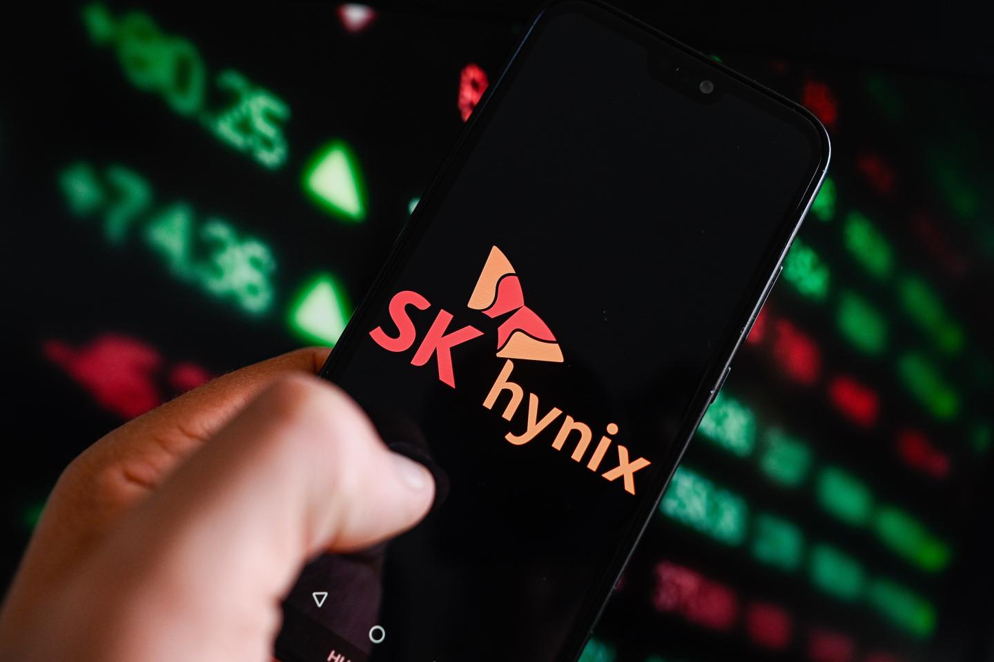 In this photo illustration, a Sk Hynix logo is displayed on a smartphone with stock market percentages in the background.