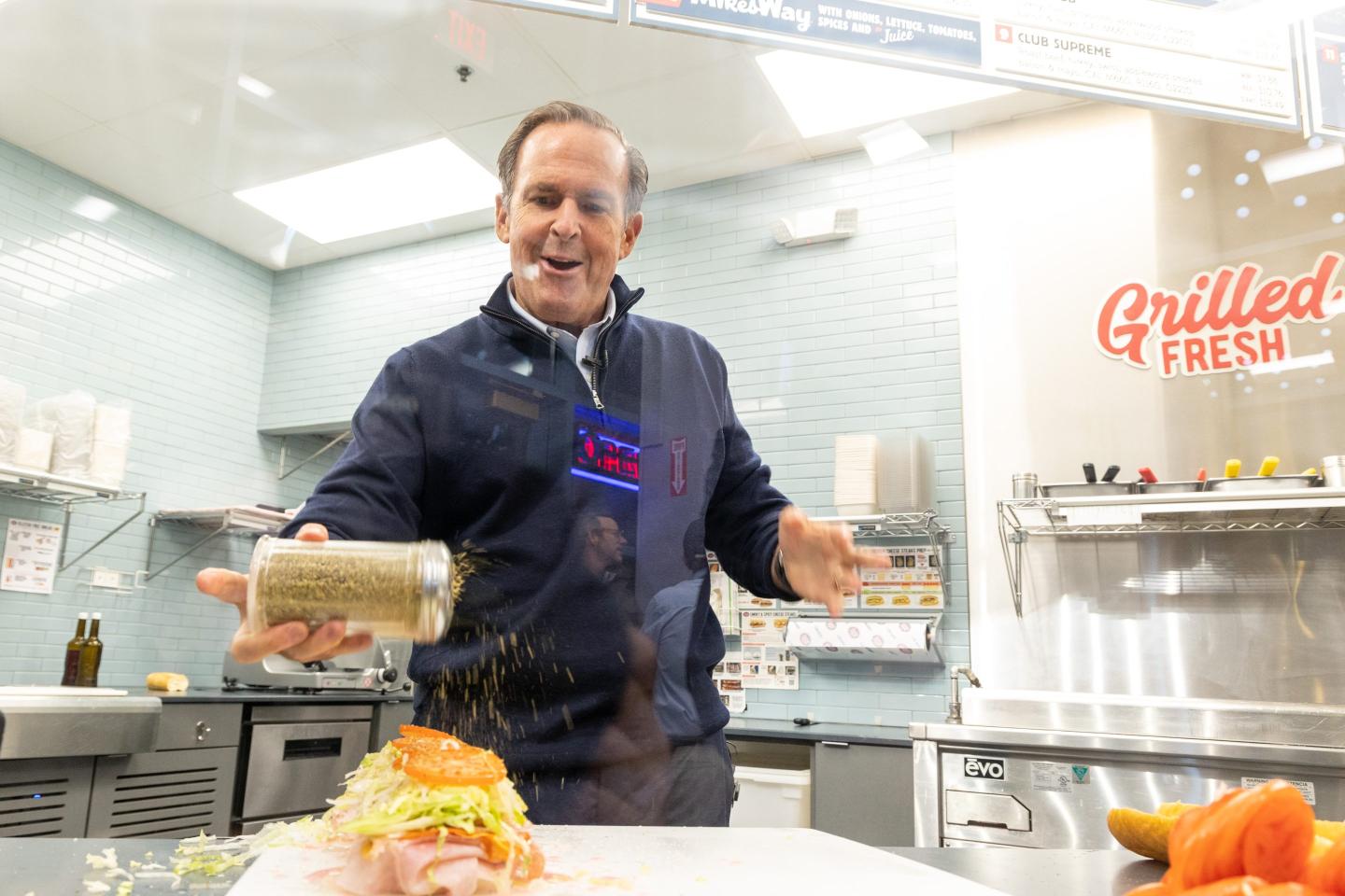 Peter Cancro shakes oregano over an open sandwich.