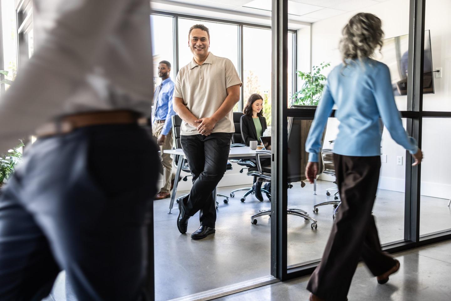 A businessman in busy modern office while employees walk past.
