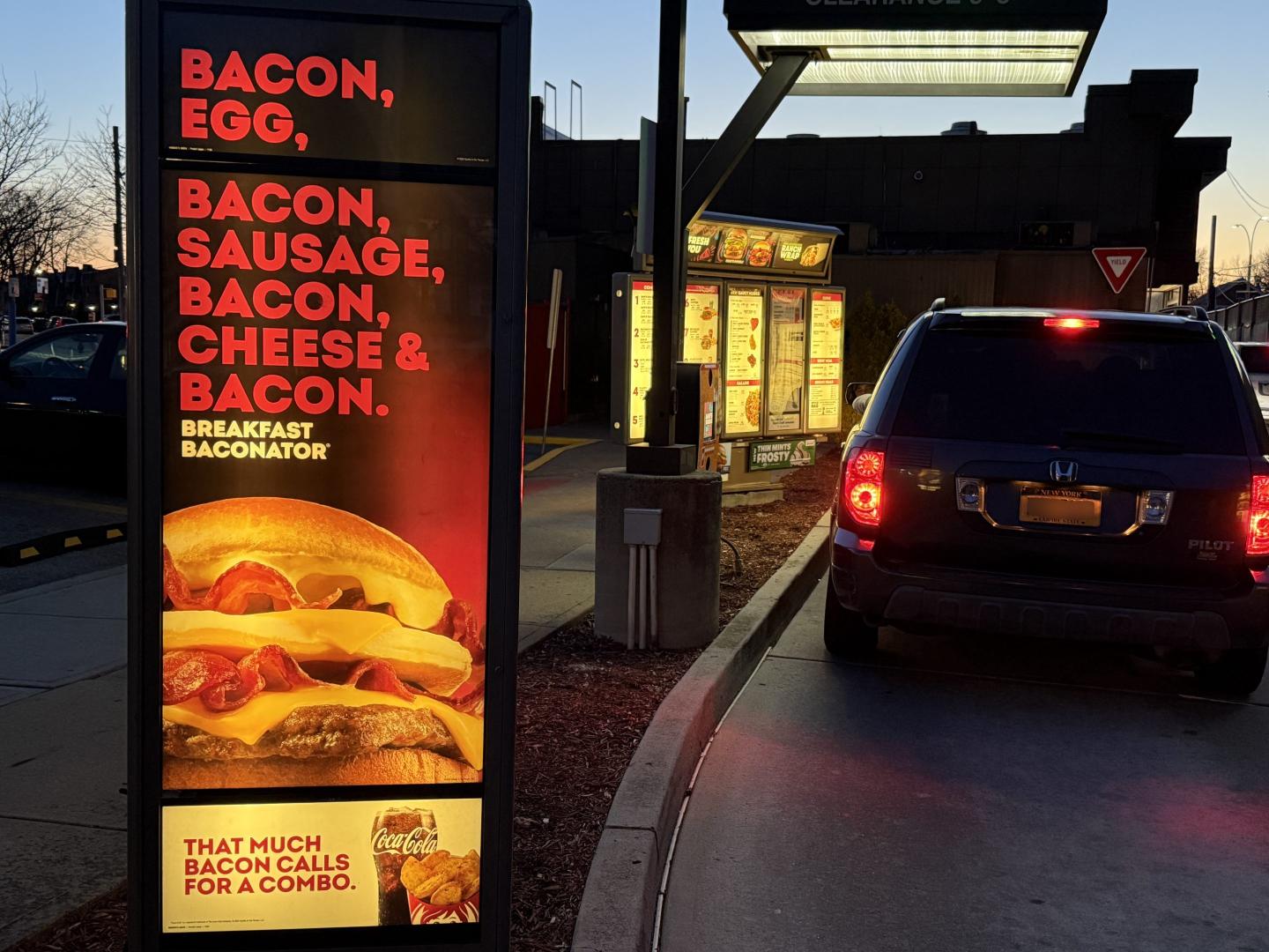A car pulls up to a Wendy's drive-through ordering machine.