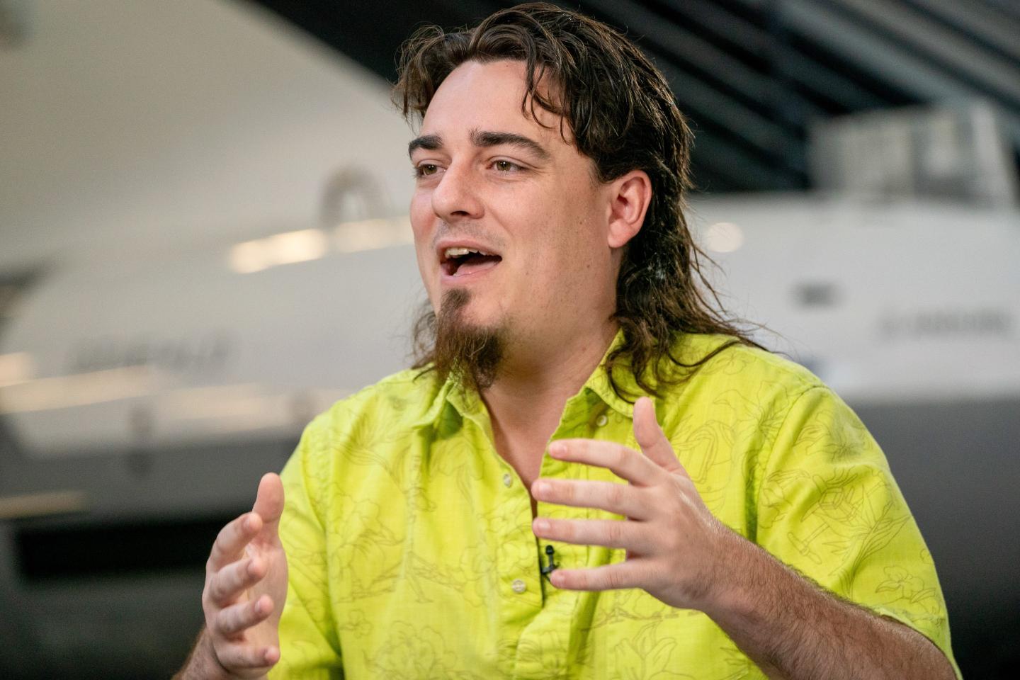 Palmer Luckey wearing a lime green shirt with his hands up gesturing
