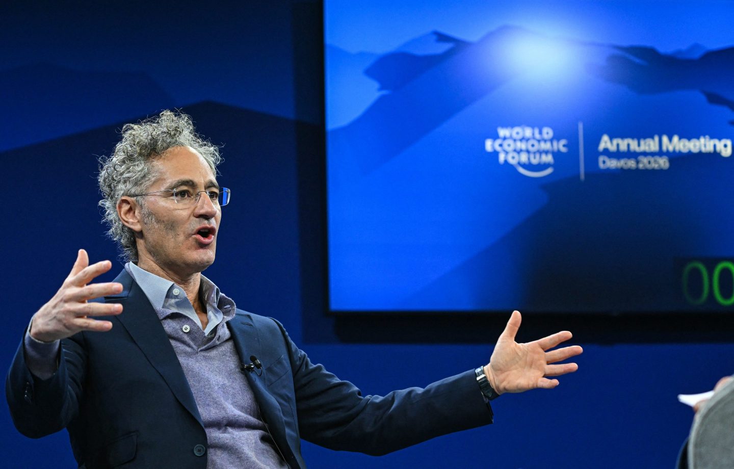 Palantir CEO Alex Karp with his arms outstretched while making a point on stage.