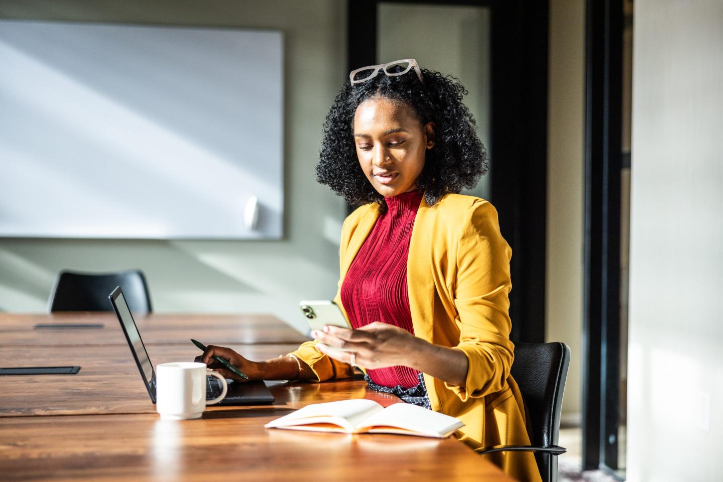 A businesswoman uses a smartphone in modern conference room.