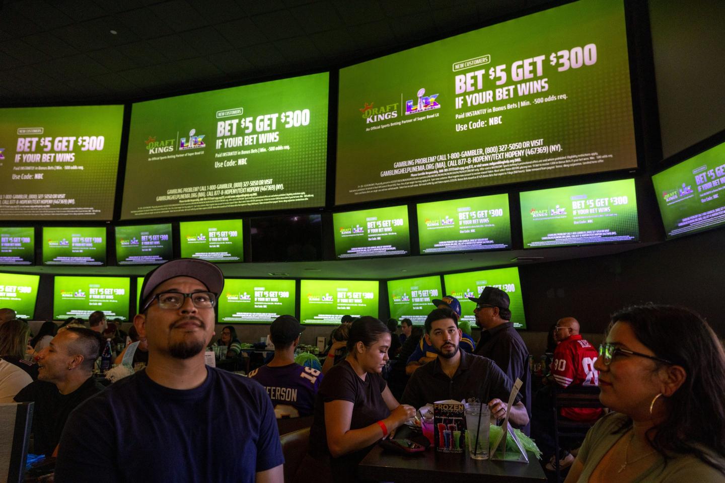 Fans Watch Super Bowl LX In California beneath tv screens with betting ads