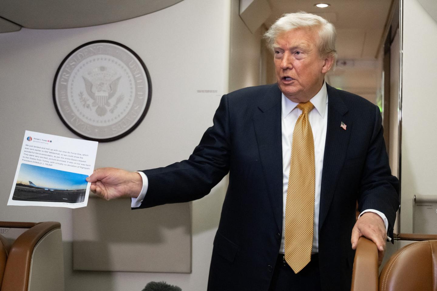 President Donald Trump holding up a printed out Truth Social post