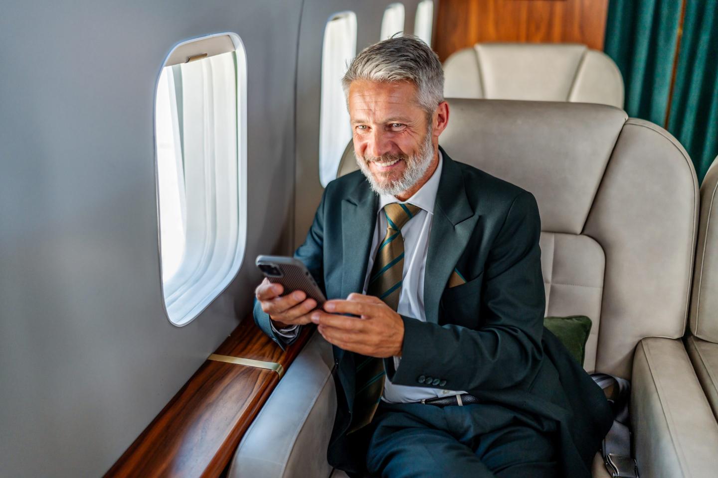 Businessman flying private jet using smartphone