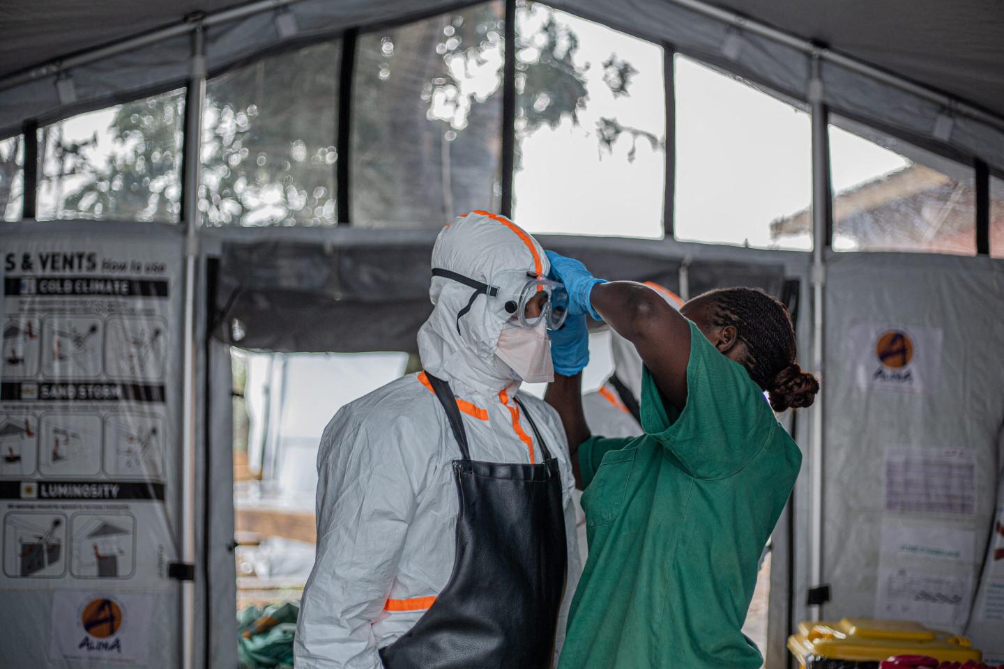 An Ebola healthcare worker is assisted putting on protective equipment in a treatment center.