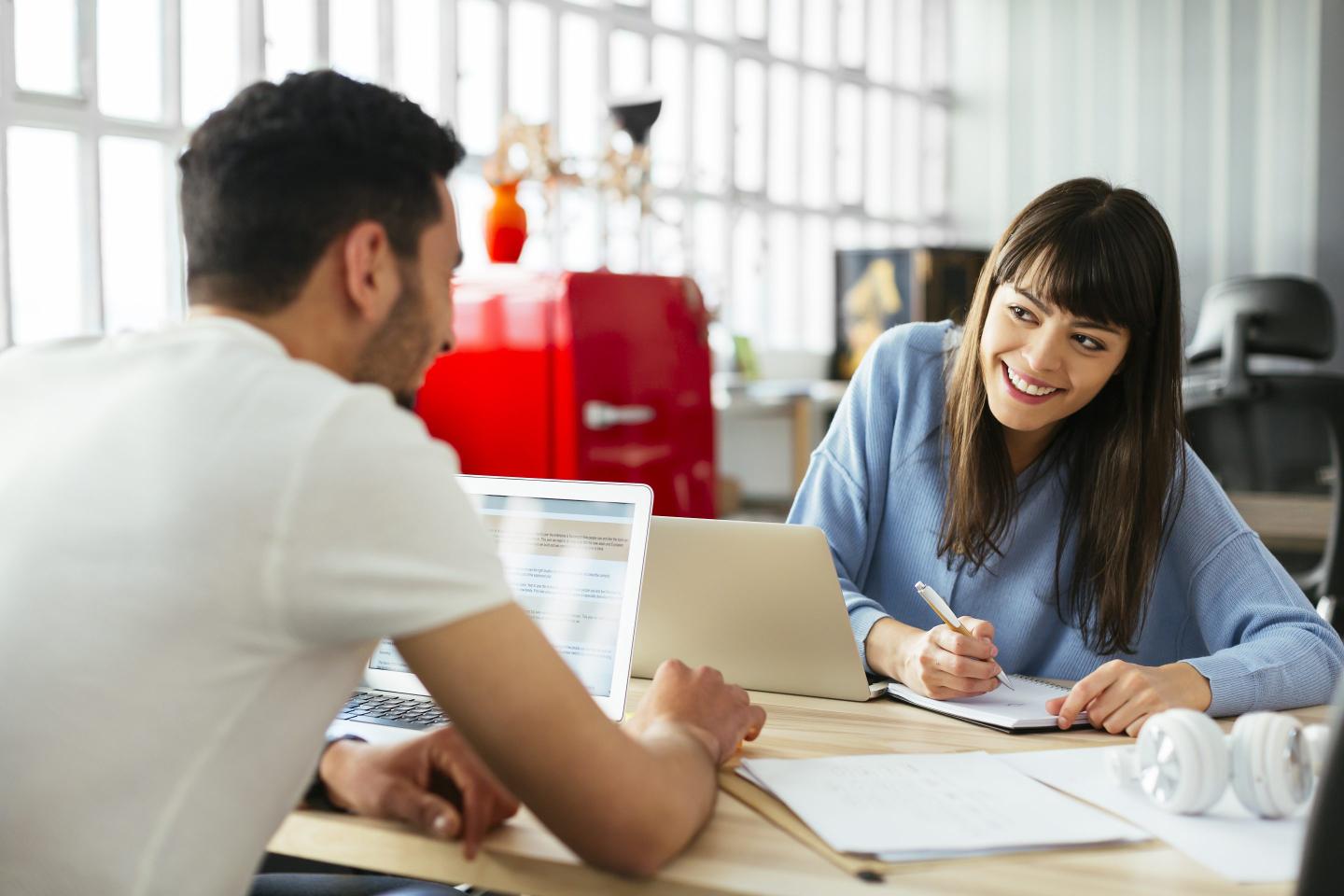 Smiling colleagues working at desk in office.