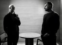Brian Armstrong (left) and David Senra (right) stand next to each other talking.