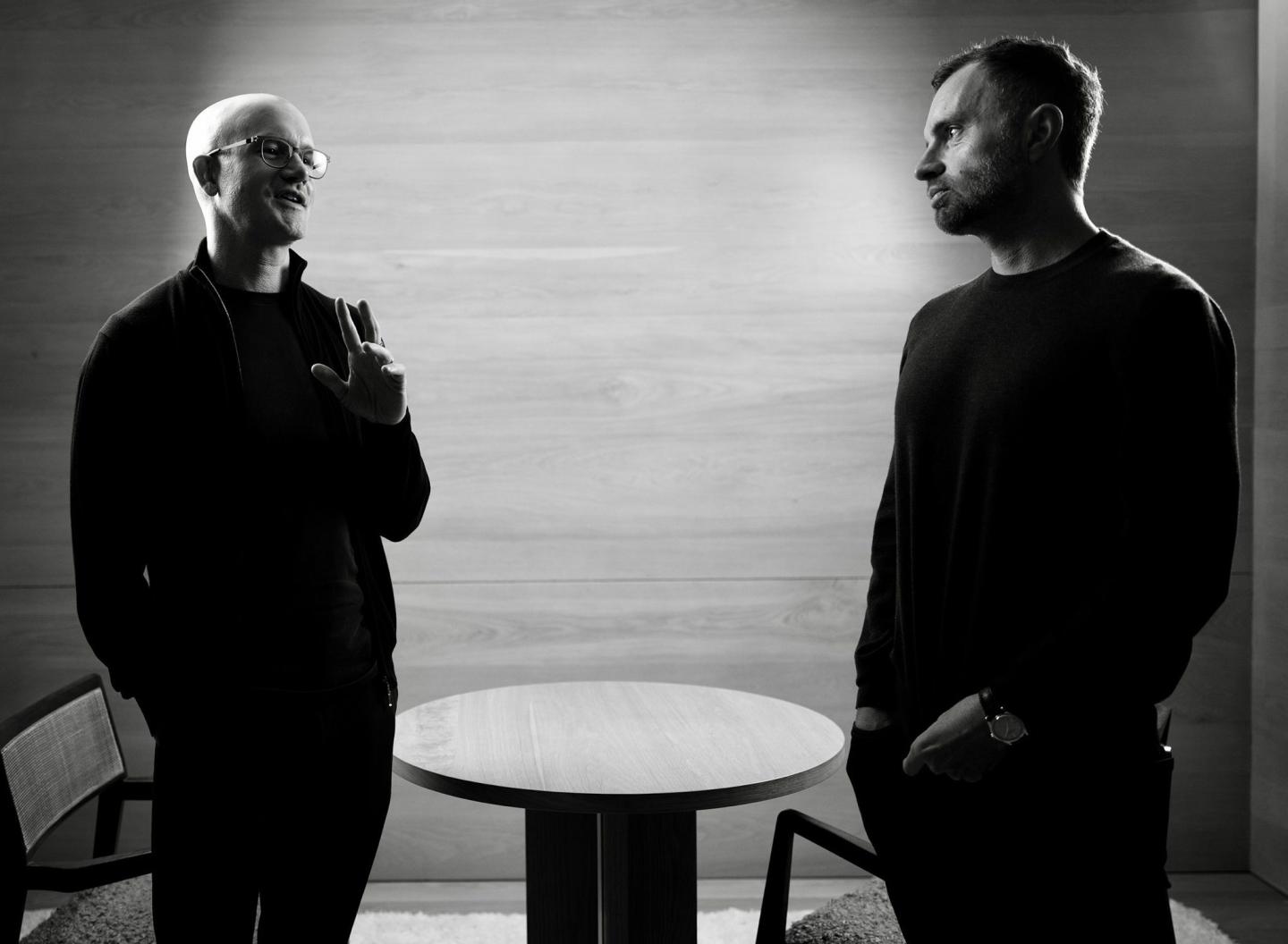 Brian Armstrong (left) and David Senra (right) stand next to each other talking.